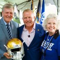 President Tom and Marcia Haas posing together at the Jamie Hosford Football Center dedication. President Haas is holding a golden football helmet.